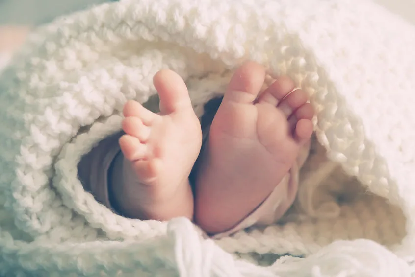 Newborn wrapped in ablanket with tiny feet